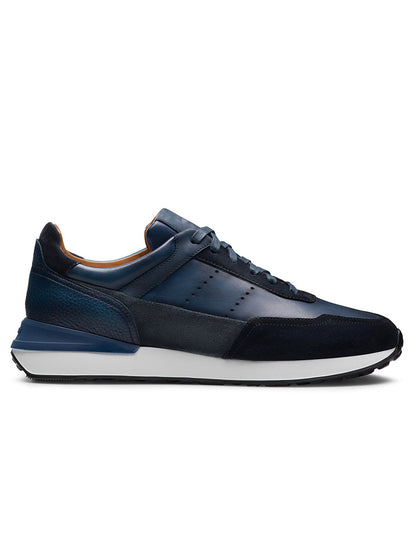The Magnanni Bravo in Indigo/Navy is a tech runner sneaker with dark blue suede and leather panels, a white sport sole, and shown in side profile against a white background.