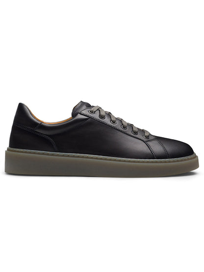 The Magnanni Camino Lo in Grey is a side-profile view of a black leather sneaker made from premium calfskin, featuring dark laces threaded through chrome eyelet accents and a thick, light grey sole.