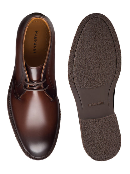 A pair of Magnanni Cervan Chukka boots in brown leather, handmade in Spain, displayed from above and below to showcase the laces, polished finish, and textured rubber sole.