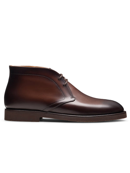 The Magnanni Cervan Chukka in Brown is a handmade leather chukka boot from Spain, featuring laces, a low heel, and a plain toe, shown on a white background.