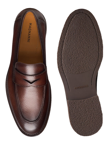 A pair of Magnanni Cervan Penny loafers in Tumbled Brown is displayed, with one shoe showing the top view and the other highlighting the sole featuring the brand name.