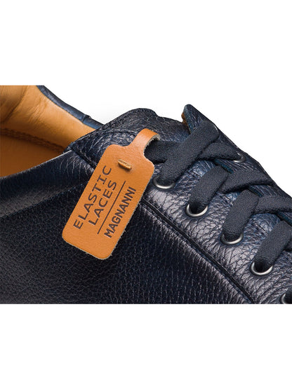 Close-up of the Magnanni Cote Lo Stretch-Lace in Tumbled Navy, a men’s dark blue leather low-top sneaker with black elastic laces and a brown "ELASTIC LACES MAGNANNI" tag, showcasing its convenient stretch-lace system.