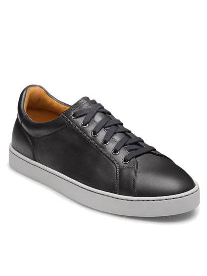 The Magnanni Cote Lo Stretch-Lace in Grey is a men’s low-top sneaker featuring grey leather, stretch laces, metal eyelets, and a white rubber sole, shown against a white background.