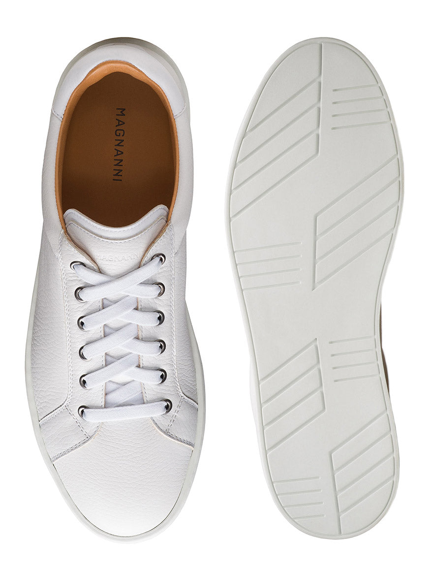 The Magnanni Cote Lo Stretch-Lace in Tumbled White/White men’s sneaker is shown from above and below, highlighting its stretch-lace system, smooth tumbled leather upper, tan lining, and rubber sole with a geometric tread pattern.