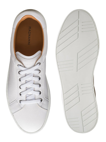 The Magnanni Cote Lo Stretch-Lace in Tumbled White/White men’s sneaker is shown from above and below, highlighting its stretch-lace system, smooth tumbled leather upper, tan lining, and rubber sole with a geometric tread pattern.