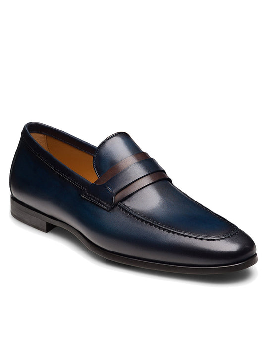 The Magnanni Daniel in Navy/Midbrown is a single dark blue leather penny loafer with a brown strap, low heel, and almond toe, made in Spain and shown on a white background.