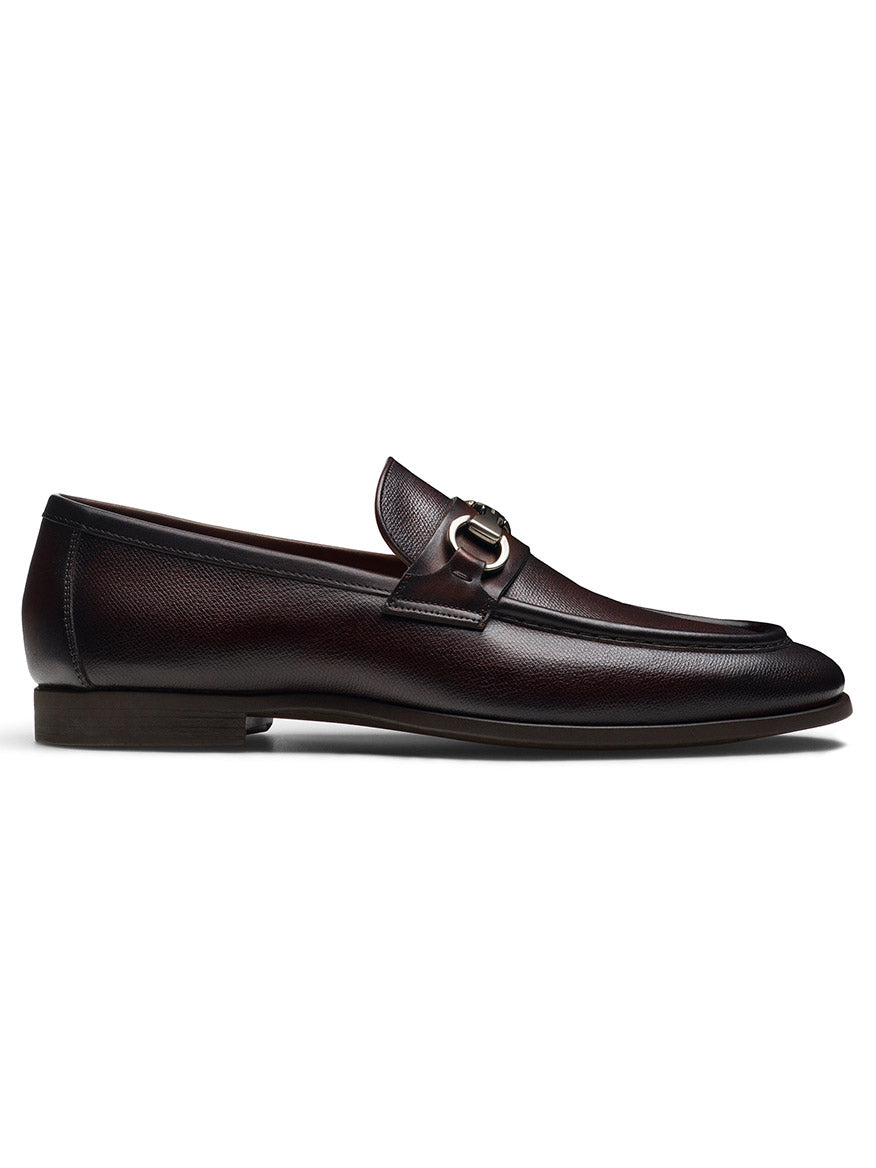 A side view of the Magnanni Darien in Brown, showcasing a dark brown textured calfskin leather loafer with a low heel, and featuring a metal bit detail on the upper part from the Línea Flex collection.