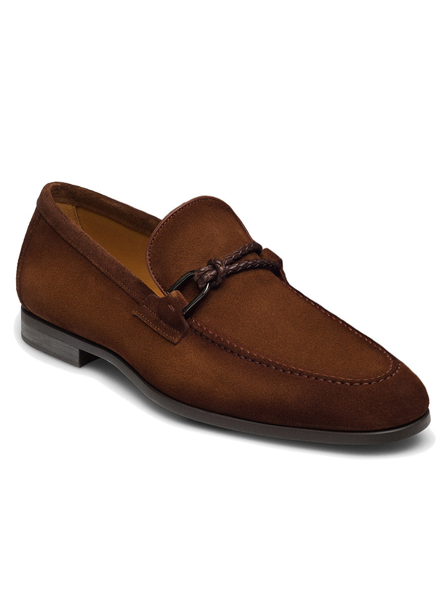 The Magnanni Destin in Cognac Suede is a contemporary loafer from the Linea Flex Collection, featuring a braided detail and a low heel. This flexible shoe offers both style and comfort with its elegant brown suede design.