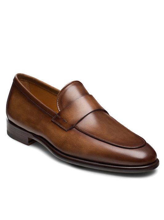 The Magnanni Duerro in Brown is a brown leather penny loafer featuring a low heel, rounded toe, and slip-on design, shown on a white background.