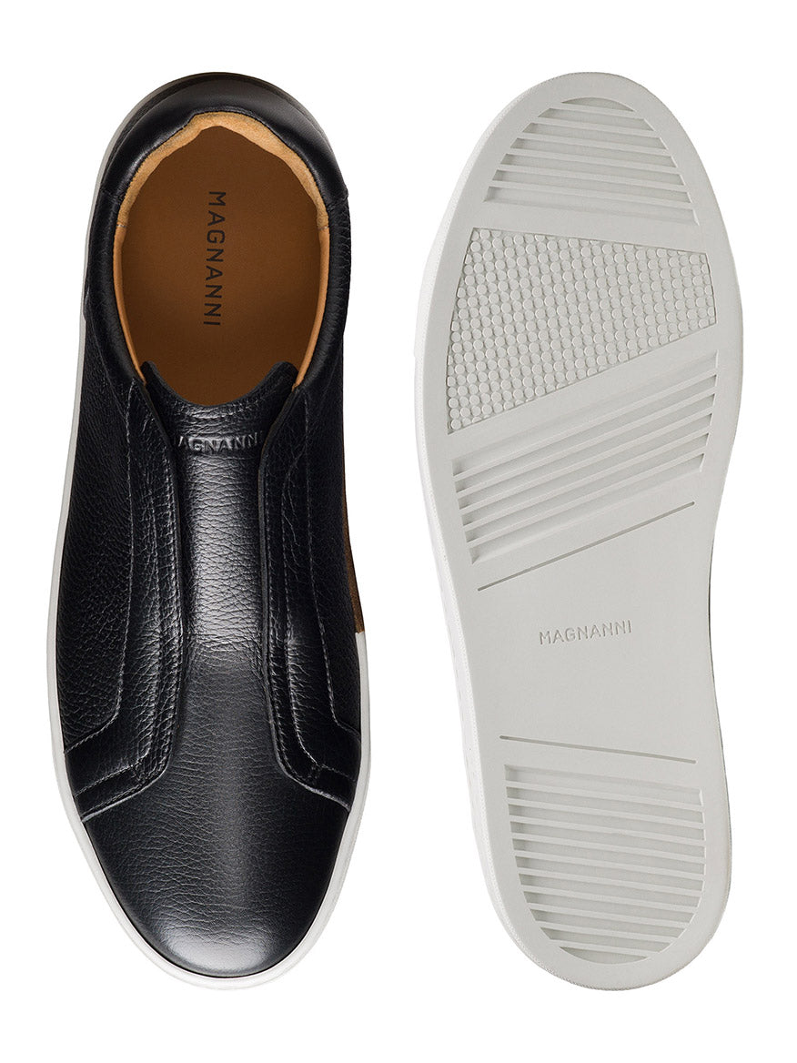 The Magnanni Gasol in Tumbled Black is a pair of black leather slip-on sneakers made in Spain, featuring hidden elastic gore and white rubber soles, shown from above and below on a white background.