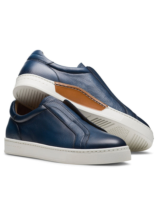 Two Magnanni Gasol in Tumbled Navy slip-on sneakers with Artesano soles; one stands upright while the other tilts, showcasing its elastic gore system and detailing.