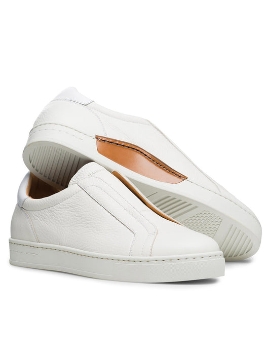 The Magnanni Gasol in Tumbled White features a pair of white leather slip-on sneakers with an elastic gore system and Artesano soles, displayed one resting on the other to highlight their simple design and smooth finish.