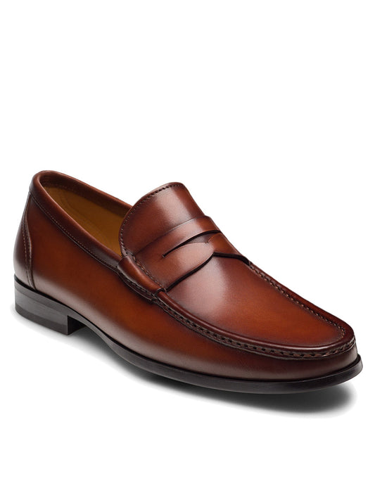 The Magnanni Gentry Penny in Cognac—a brown leather loafer with a low heel and stitching detail—features a classic moccasin design, displayed against a plain white background.