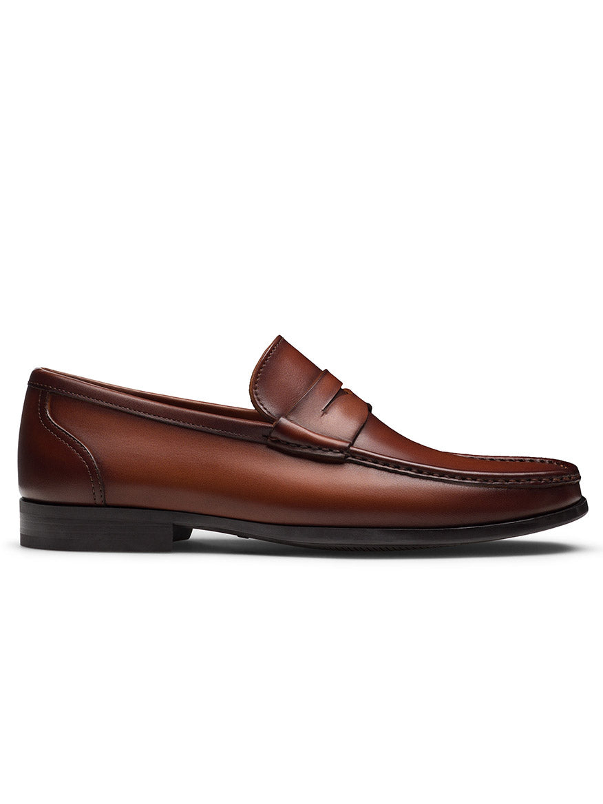 The Magnanni Gentry Penny in Cognac is a classic brown leather slip-on loafer with a low heel and stitched details, shown in profile against a white background.