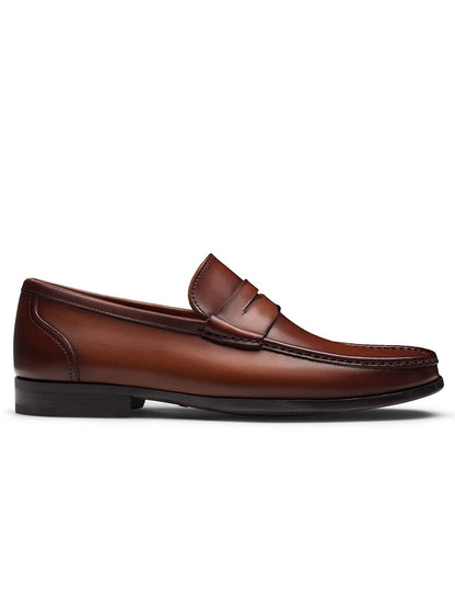 The Magnanni Gentry Penny in Cognac is a classic brown leather slip-on loafer with a low heel and stitched details, shown in profile against a white background.