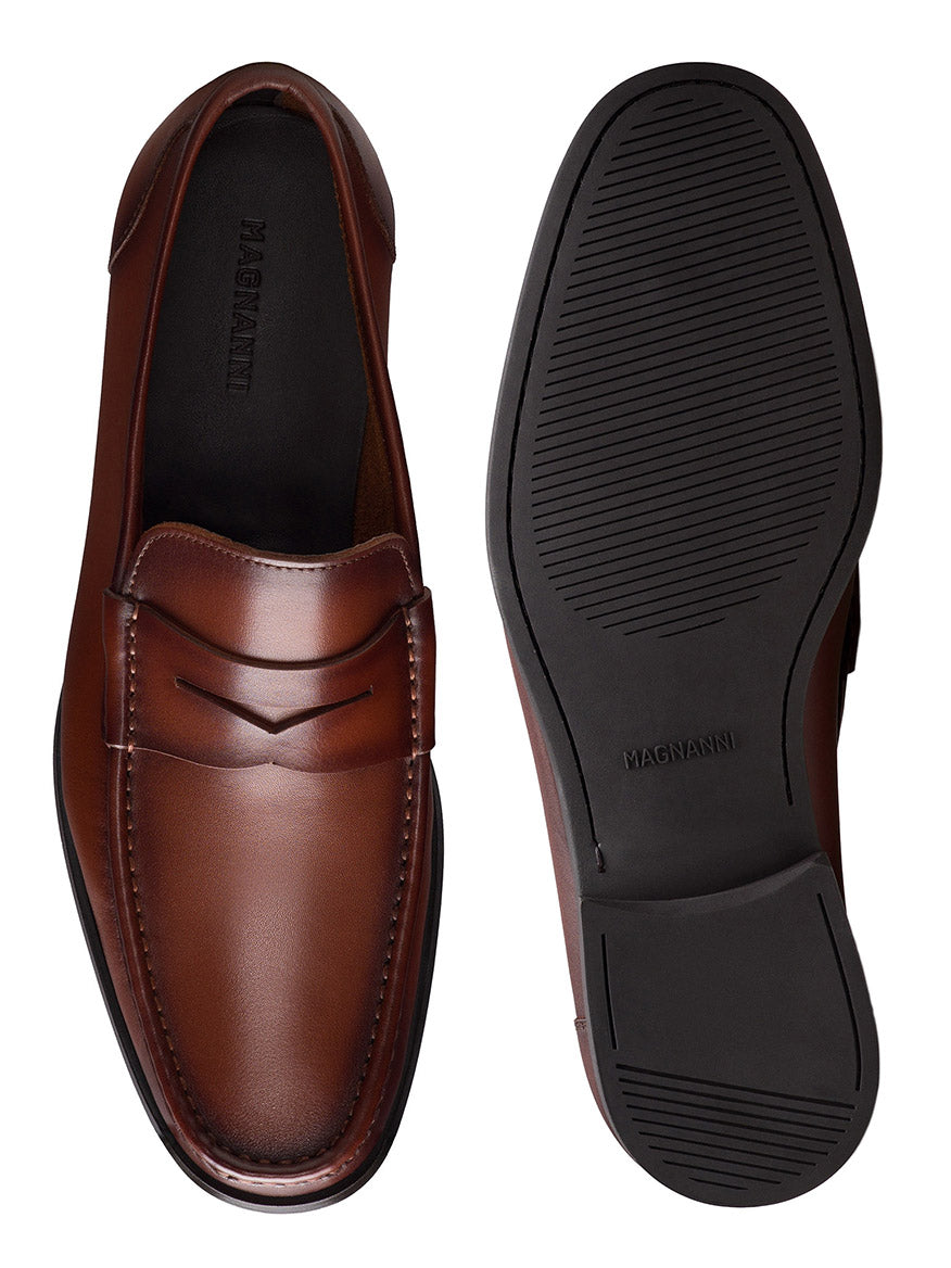 A pair of Magnanni Gentry Soft Penny loafers in Brandy, one shown from the top and the other showcasing the black rubber sole.