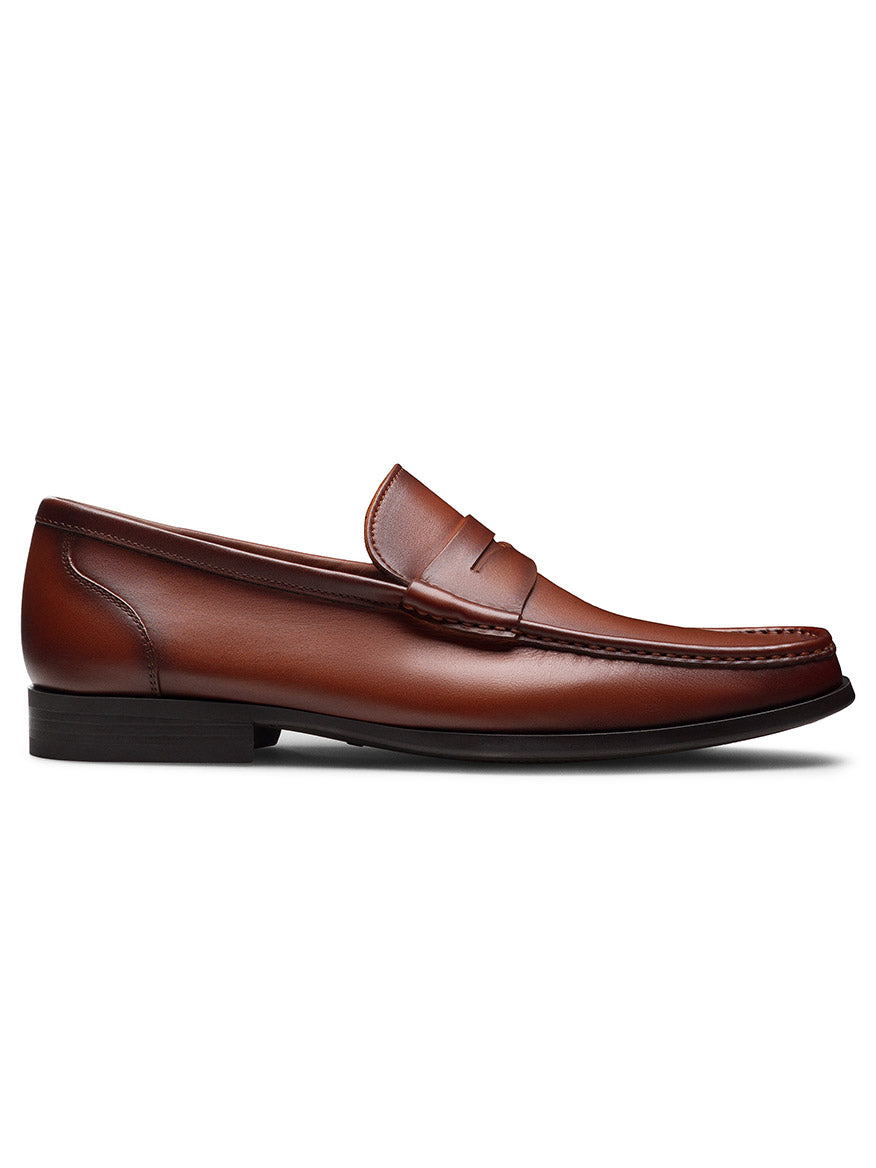 The Magnanni Gentry Soft Penny in Brandy is a single brown leather loafer with moccasin construction, unlined interior, and a low black heel, shown from the side on a white background.
