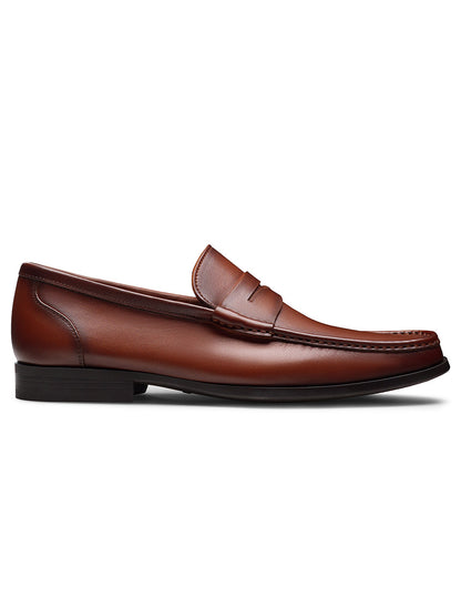 The Magnanni Gentry Soft Penny in Brandy is a single brown leather loafer with moccasin construction, unlined interior, and a low black heel, shown from the side on a white background.