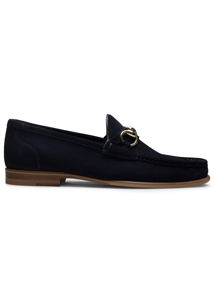 The Magnanni Giancarlo in Navy Suede is a hand-stitched loafer with a low wooden heel and gold metal bit detail on the upper, made in Spain and shown from the side.