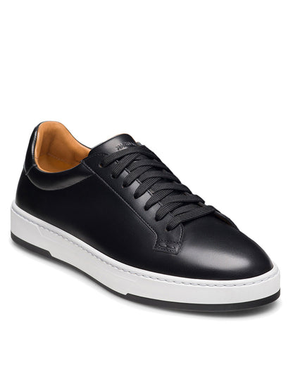 Magnanni Kona Lo in Black—a handmade men’s low-top sneaker crafted in Portugal, featuring black leather, black laces, a tan inner lining, and a white rubber sole—shown angled to the left against a white background.