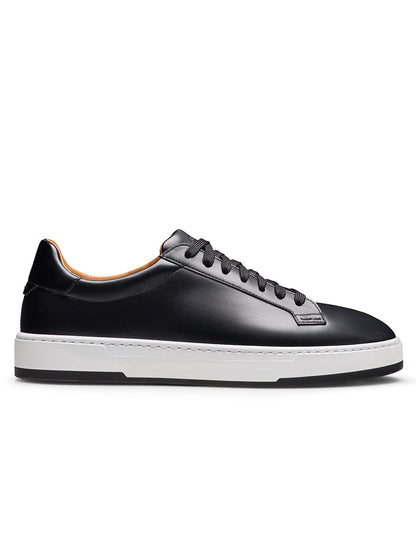 The Magnanni Kona Lo in Black is a men’s black leather low-top sneaker featuring black laces and a white rubber sole, handmade in Portugal and shown in profile against a plain white background.