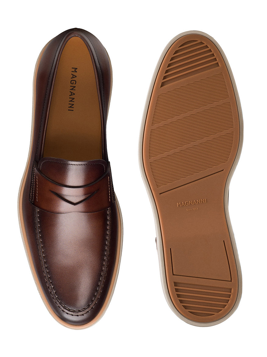 The Magnanni Lalo II in Brown is a men's loafer shown from top and bottom, highlighting brown leather, stitching details, and rubber soles with textured patterns—an elegant shoe with timeless style.