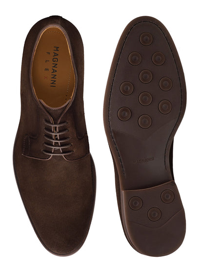 A pair of Magnanni Lanai in Midbrown Suede dress shoes is shown from above; the left shoe displays its upper surface, while the right smart-casual derby is placed upside-down, showcasing the sole with round pattern details and a cushioned footbed.