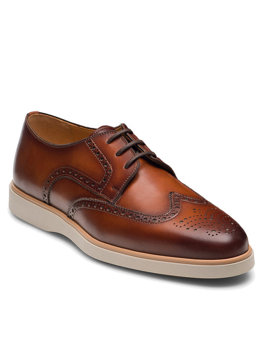 Magnanni Leonel II in Cognac: a premium brown leather hybrid wingtip derby with brogue detailing and a white rubber sole, shown angled on a plain background.