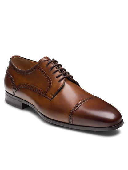 The Magnanni Macsen in Tabaco is a brown leather brogue dress shoe with a cap toe, dark brown sole, and detailed broguing. Featuring handcrafted Bologna construction, this luxury footwear is shown elegantly on a white background.