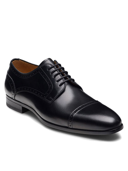 The Magnanni Macsen in Black is a handcrafted black brogue dress shoe with laces, intricate detailing, and a low heel—an elegant example of luxury footwear displayed against a white background.