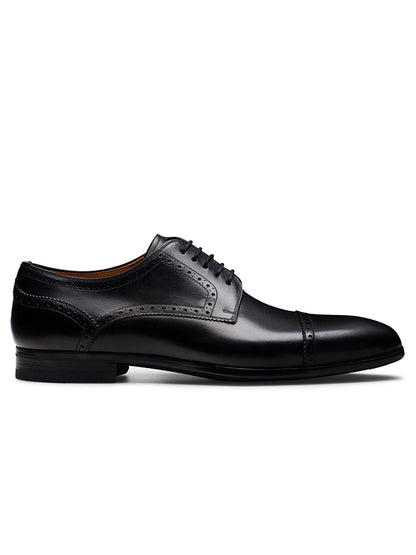 The Magnanni Macsen in Black is a leather brogue dress shoe with a cap toe and decorative stitching, shown side-on against a white background—ideal for luxury footwear enthusiasts.