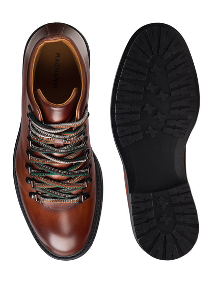 Top and bottom views of the Magnanni Montana X in Cognac, a modern hiking boot featuring brown leather, multicolored laces, and a rugged black rubber sole.