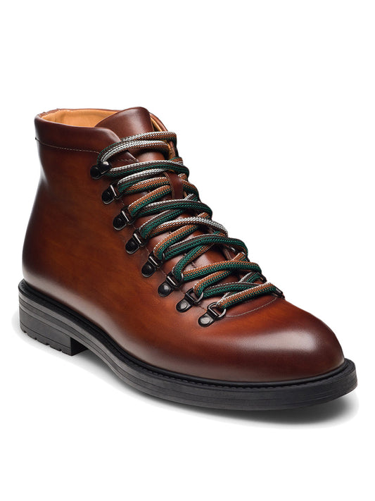 The Magnanni Montana X in Cognac is a modern hiking boot with brown leather, black and green striped laces, a black sole, and metal eyelets—perfect for stylish outdoor adventures. Shown on a white background.