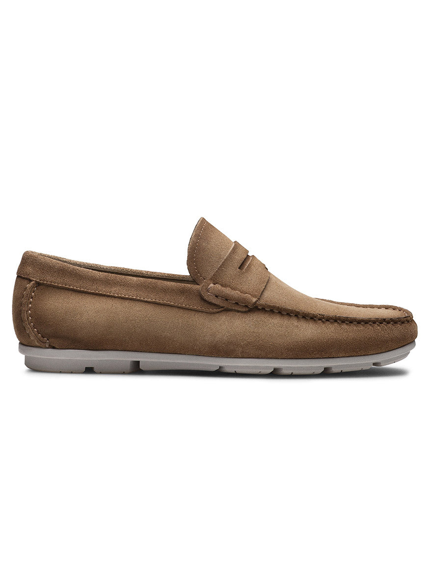 The Magnanni Monterey Keeper in Roccia Suede is a tan suede penny loafer with a moccasin toe, handcrafted leather accents, and a white rubber sole, shown in profile on a white background.