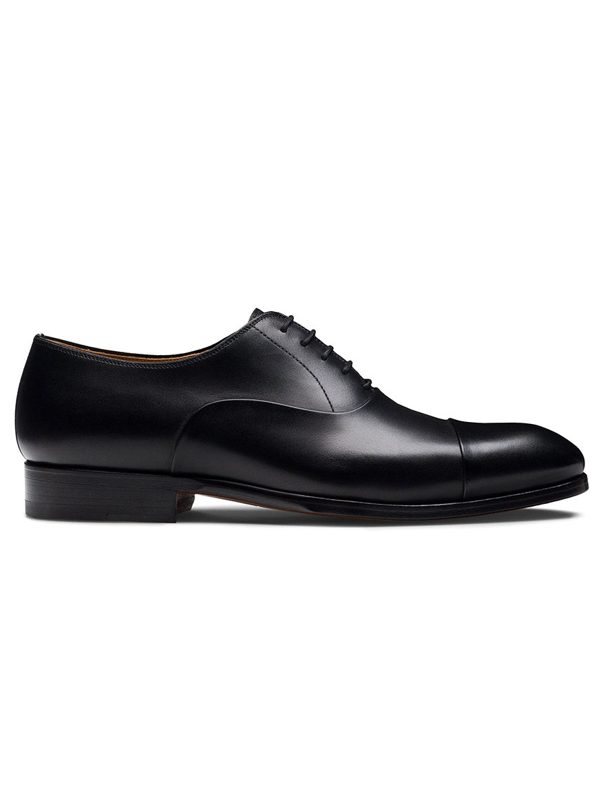The Magnanni Naxos in Black is a leather Oxford dress shoe with closed lacing and a cap toe, shown in side profile on a white background—ideal men’s formal footwear to complement any tuxedo.