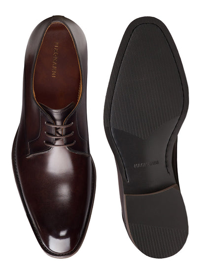The Magnanni Omero in Brown is a polished men's leather derby shoe shown from the top and bottom, featuring laces, a textured rubber sole, and classic plain toe styling—a modern essential.