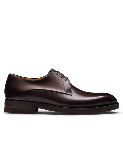 The Magnanni Omero in Brown is a men's single dark brown leather plain toe derby shoe with laces, a low heel, and smooth finish, shown from the side against a white background.