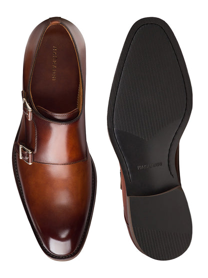 The Magnanni Omnia in Cognac are elegant brown leather double monk strap dress shoes with silver buckles and black rubber soles, shown from top and bottom views.