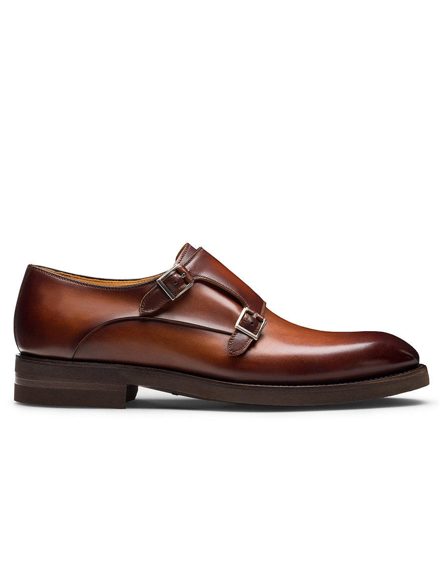 The Magnanni Omnia in Cognac is a brown leather double monk strap dress shoe with two silver buckles, low heel, and smooth polished finish, offering an elegant side profile.