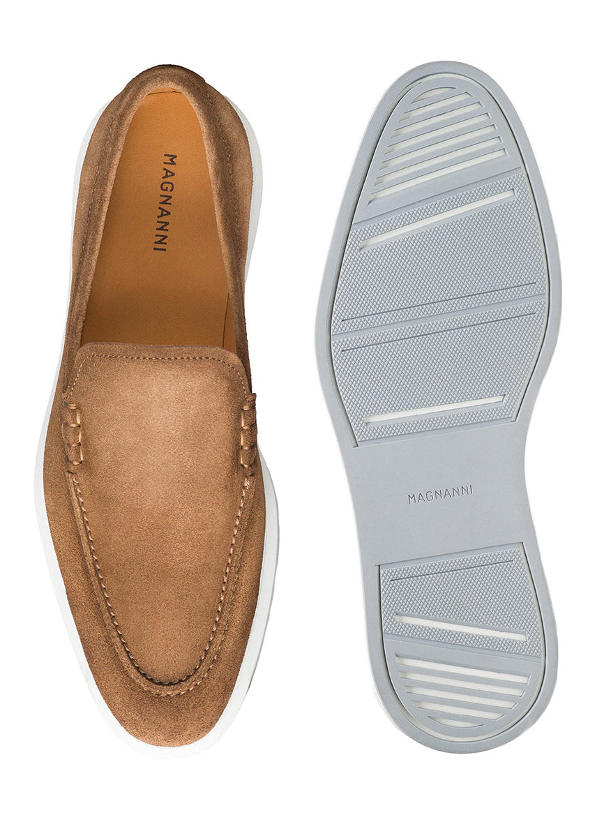 The Magnanni Orion in Taupe Suede is shown from the top and bottom, featuring a white textured rubber sole and visible stitching details around the upper for a modern dress sneaker-inspired style.
