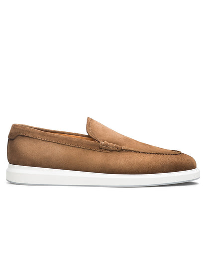 The Magnanni Orion in Taupe Suede is a brown suede loafer with visible stitching, a white rubber sole, and an elegant dress silhouette, shown in profile against a white background.