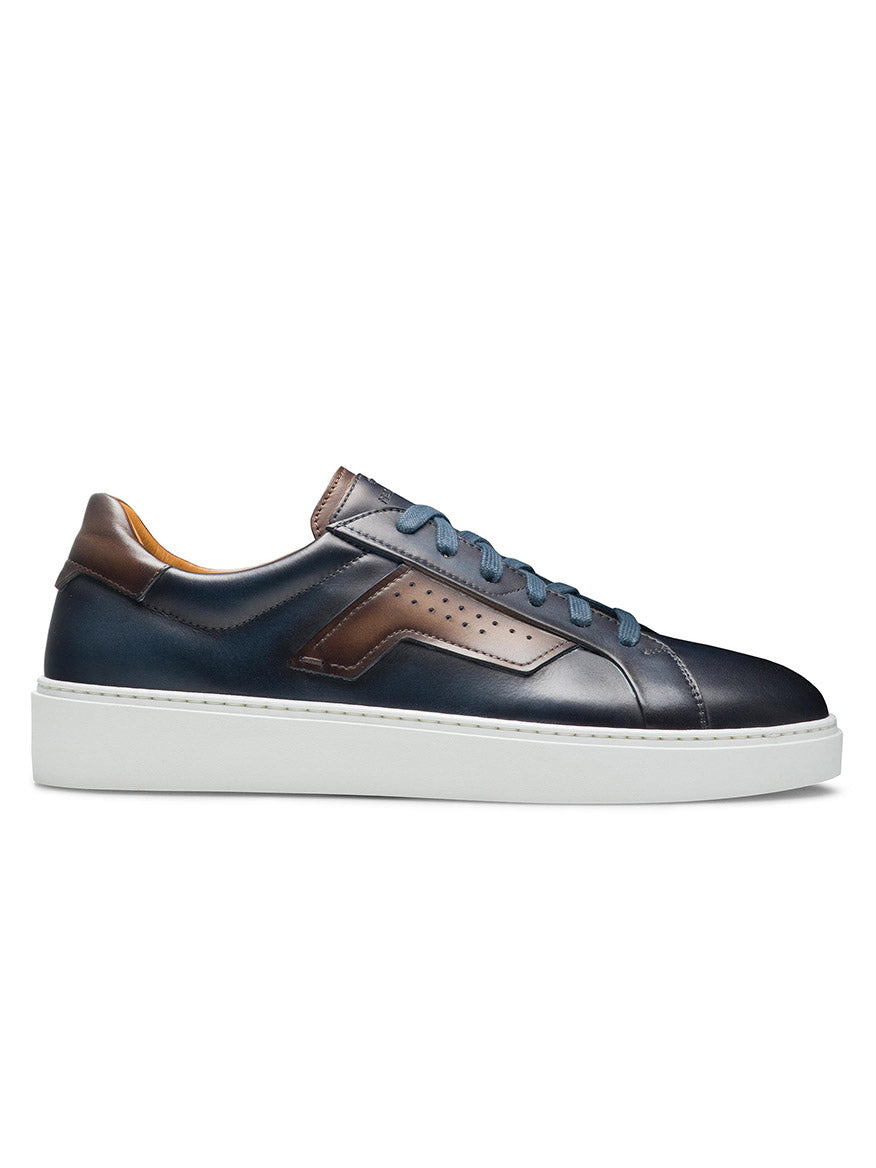 Side view of a navy blue low-top Magnanni Phoenix in Navy/Brown with brown wing-inspired leather accents, perforated detailing on the side, blue laces, and a white rubber sole, embodying a sophisticated sporty appeal.