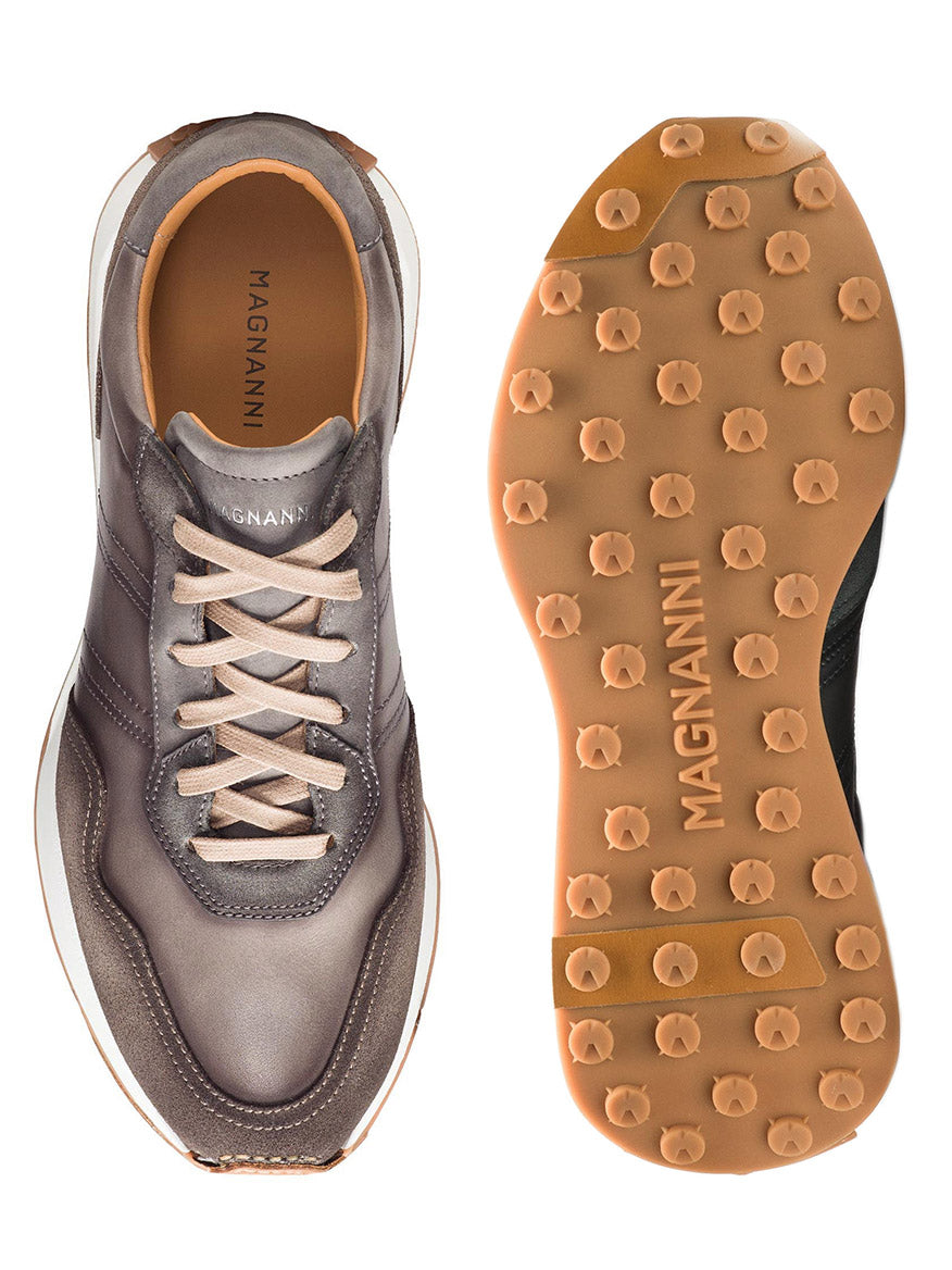 Pair of Magnanni Romero II in Grey/Taupe from the Magnanni Trainer collection, showcasing a hand-stitched leather finish. The top view of the left shoe and sole view of the right shoe reveal brown and gray coloring with a distinctive tread pattern featuring raised dots.