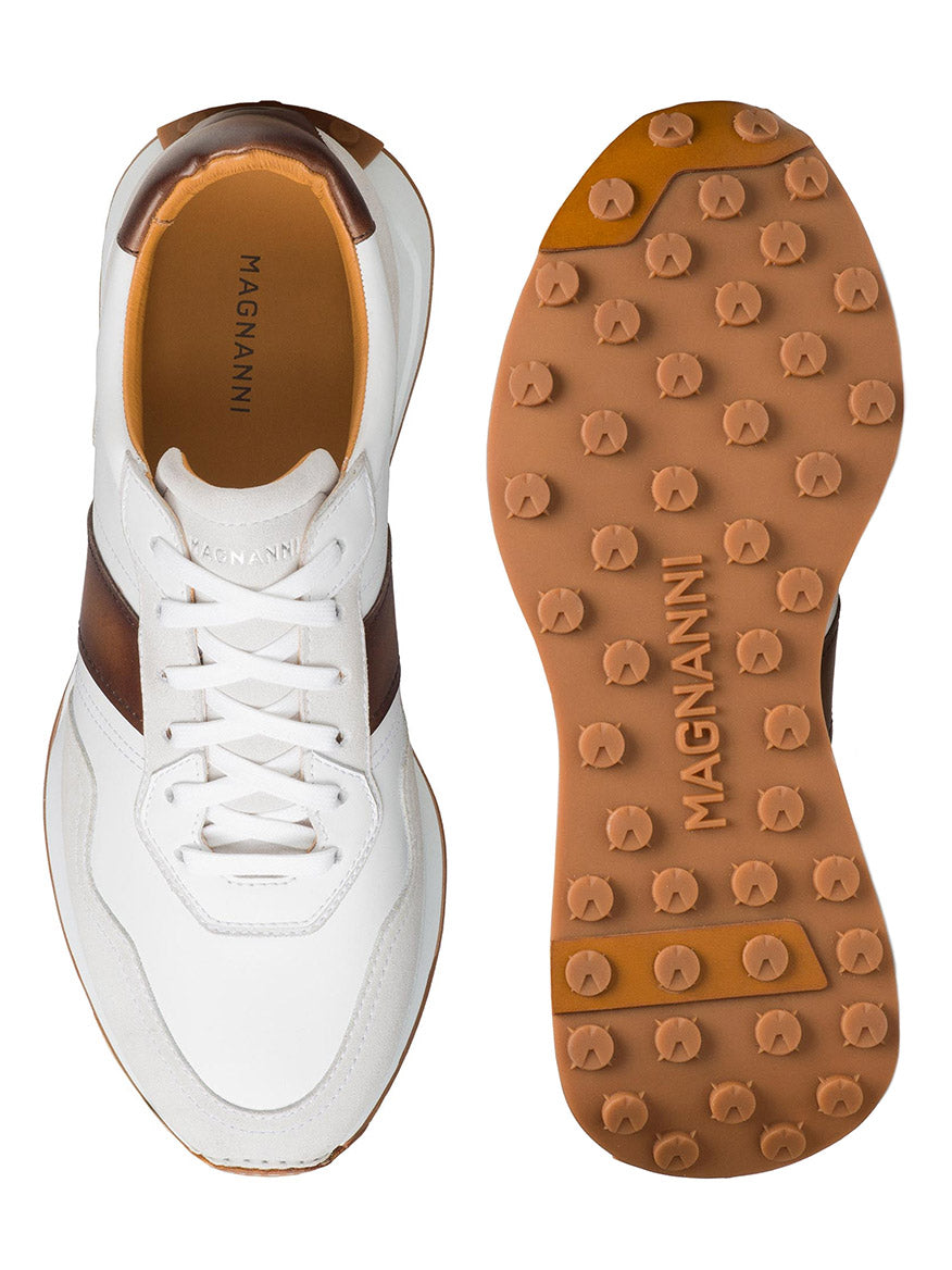 Top and bottom view of a sophisticated sport sneaker—the Magnanni Romero II in White/Brown features brown hand-stitched leather accents and a mixed media upper, complete with a tan rubber sole sporting pronounced circular treads.