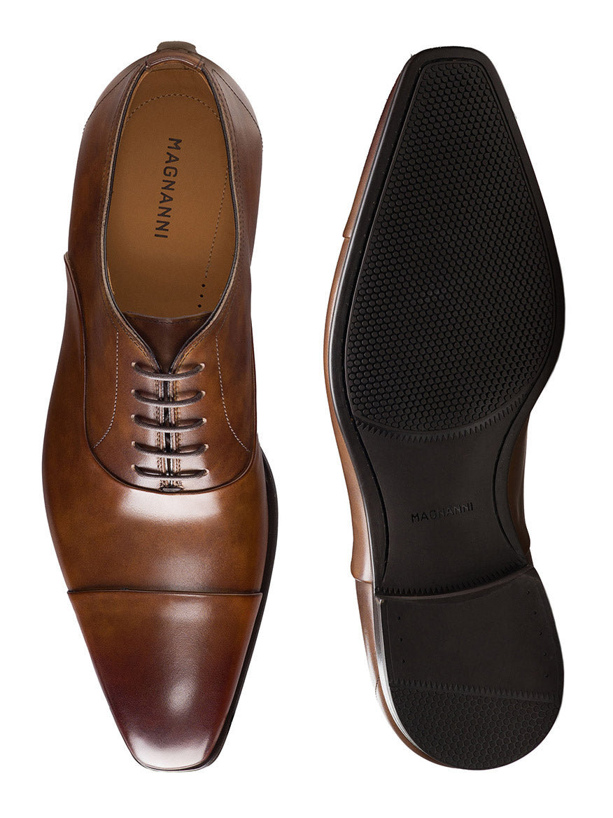 The Magnanni Santiago in Tabaco men’s leather oxford dress shoes are shown from the top and bottom, featuring a closed lacing system, cap toe design, and rubber sole detail.