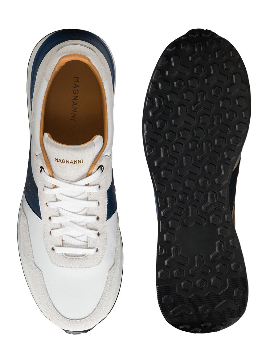 Top and bottom views of the Magnanni Sentro in White/Navy—a minimalist sneaker with blue accents, tan lining, black textured rubber sole, and premium full-grain leather. "Magnanni" label is visible on the inside.