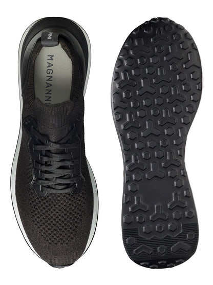 A single black Magnanni Stratus LyteKnit sneaker with a stylish knit design, featuring the Magnanni logo on the cushioned footbed, is showcased from both top and bottom views to highlight the tread pattern on the sole.