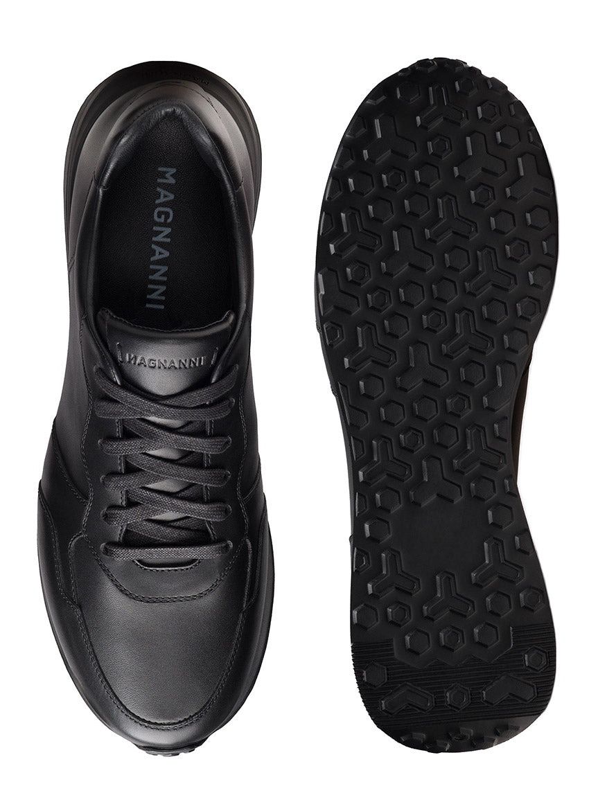 A pair of Magnanni Syros in Black sneakers, made in Spain with luxurious leather, shown from top and sole views, featuring a lace-up design and textured rubber outsole.
