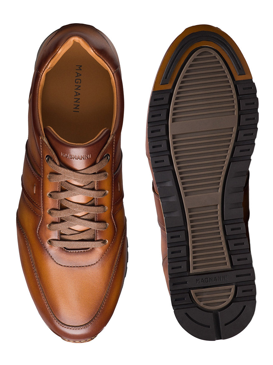 The Magnanni Ventura in Cuero sneakers, crafted from premium brown leather, are shown from the top and sole with matching brown laces and a black rubber tread.
