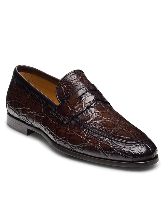 The Magnanni Vicente Croc in Brown is a leather loafer with a crocodile skin texture, featuring a low heel and a penny slot on the upper surface.